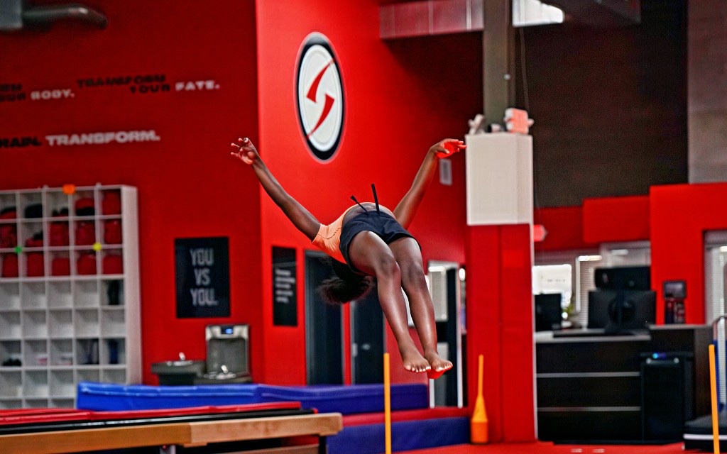 Vortex athlete flying through a back layout in the gym