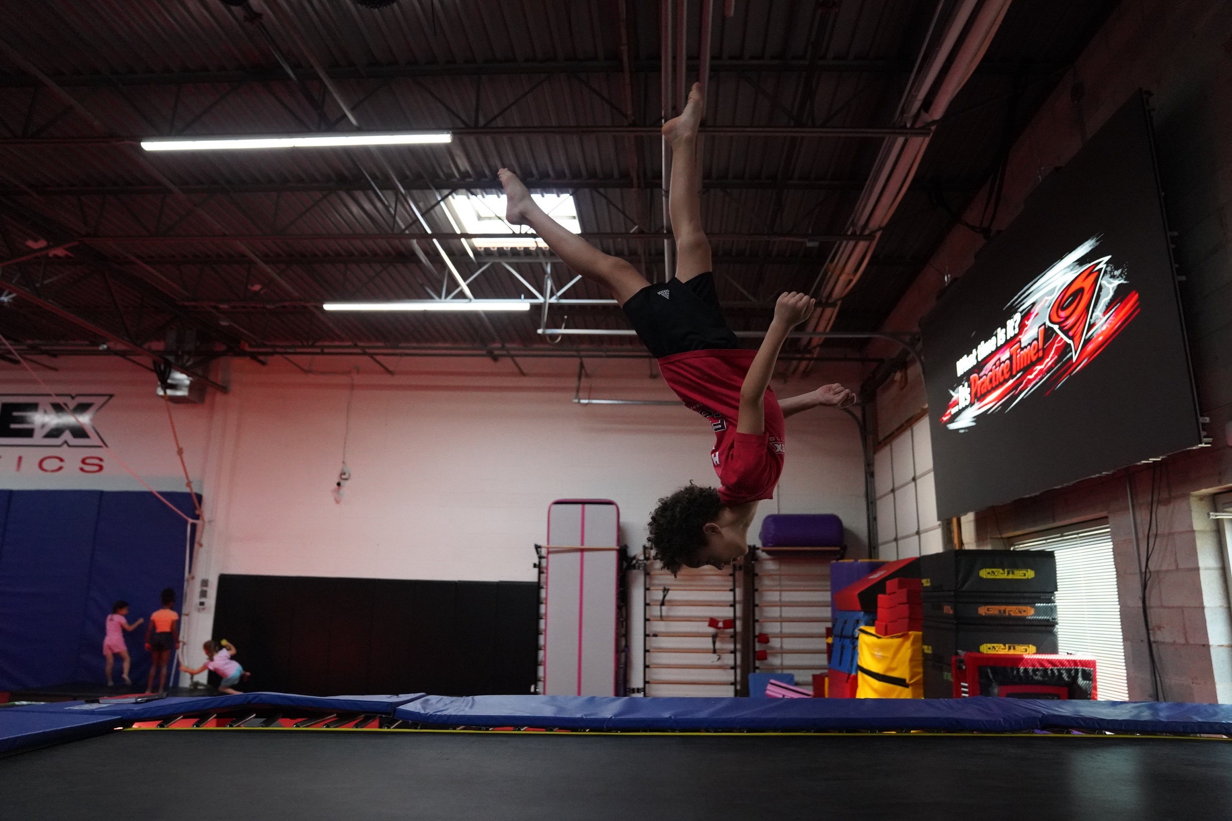 A Vortex athlete performing an inverted skill above the trampoline